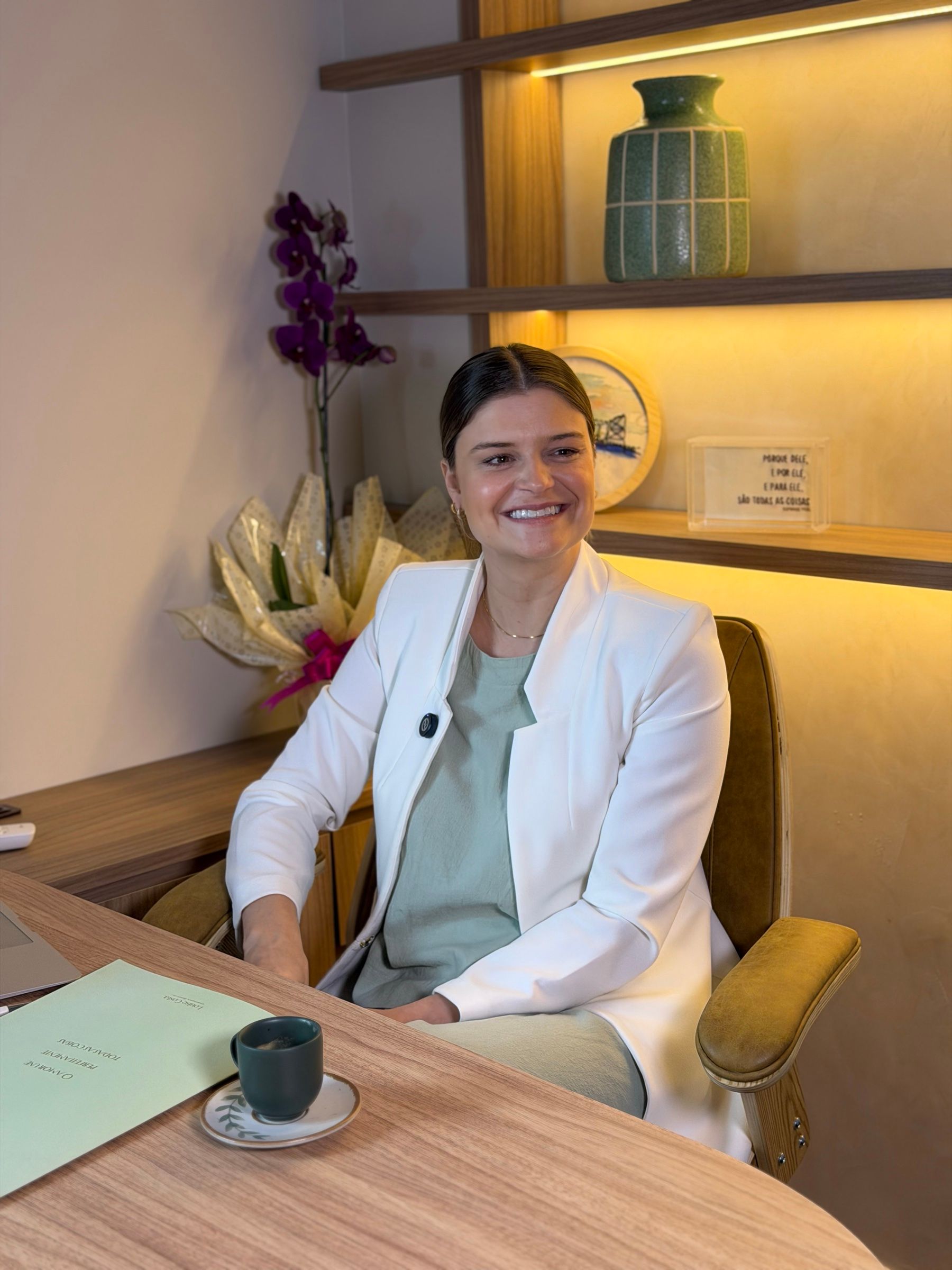 Dra. Louise Costa, ginecologista em Florianópolis, sorrindo à mesa do seu consultório